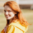 Woman in yellow jacket smiling outdoors