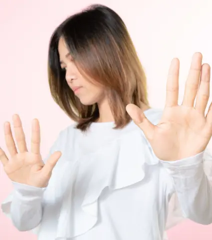 Woman in white shirt gesturing stop with hands.