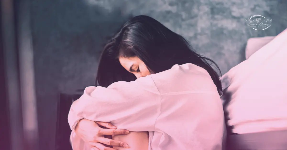 Woman in pink sweater sitting pensively indoors.