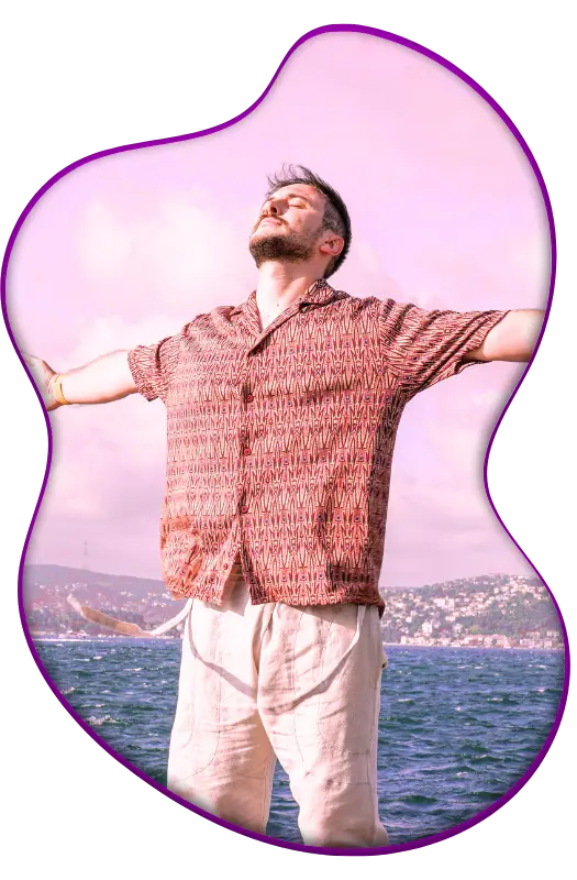 Man enjoying coastal breeze with arms open wide.