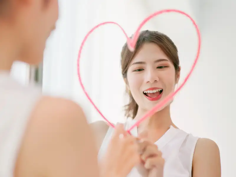 Woman drawing heart on mirror