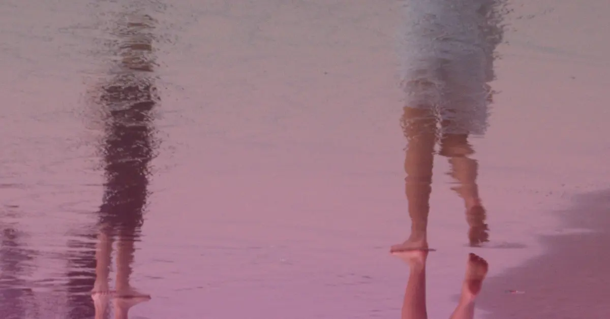 Reflections of people walking on wet sand