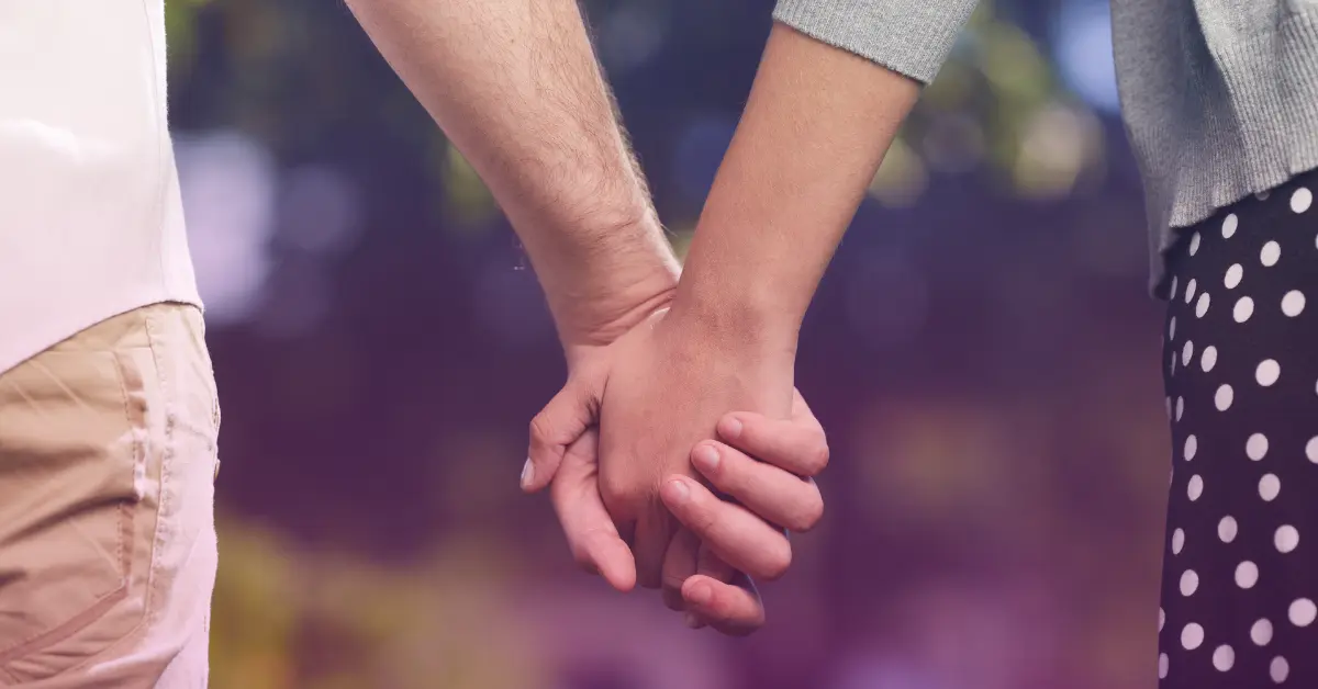 Couple holding hands outdoors, love and connection.