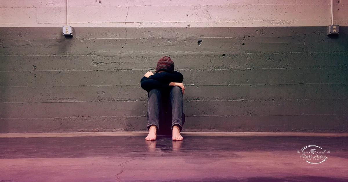 Person sitting alone against wall indoors.