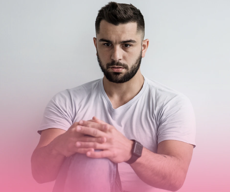 Man wearing white shirt, seated against plain background.