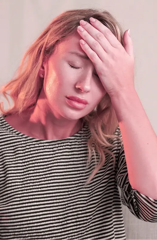 Woman with headache, hand on forehead, striped top.