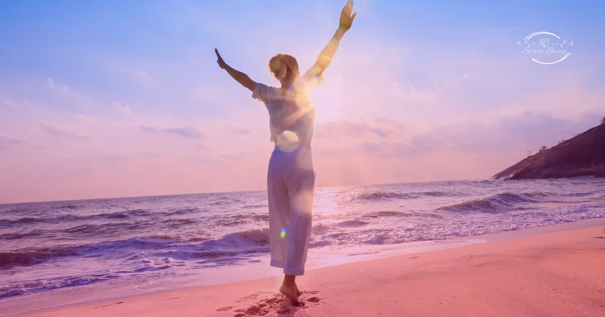 Person celebrating on a beach at sunset.