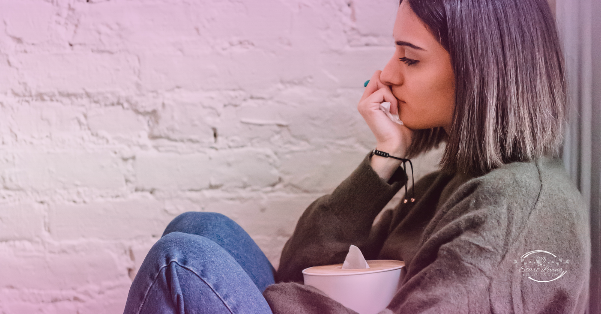 Woman sitting and thinking, holding a tissue box.