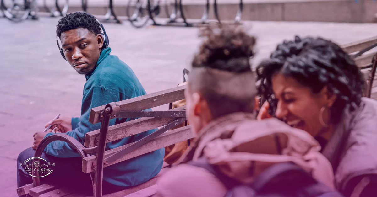 Man sitting on bench, people chatting in foreground.