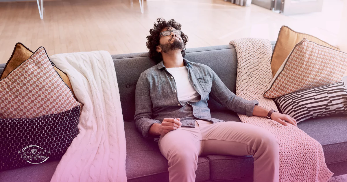 Man relaxing on sofa with decorative pillows.